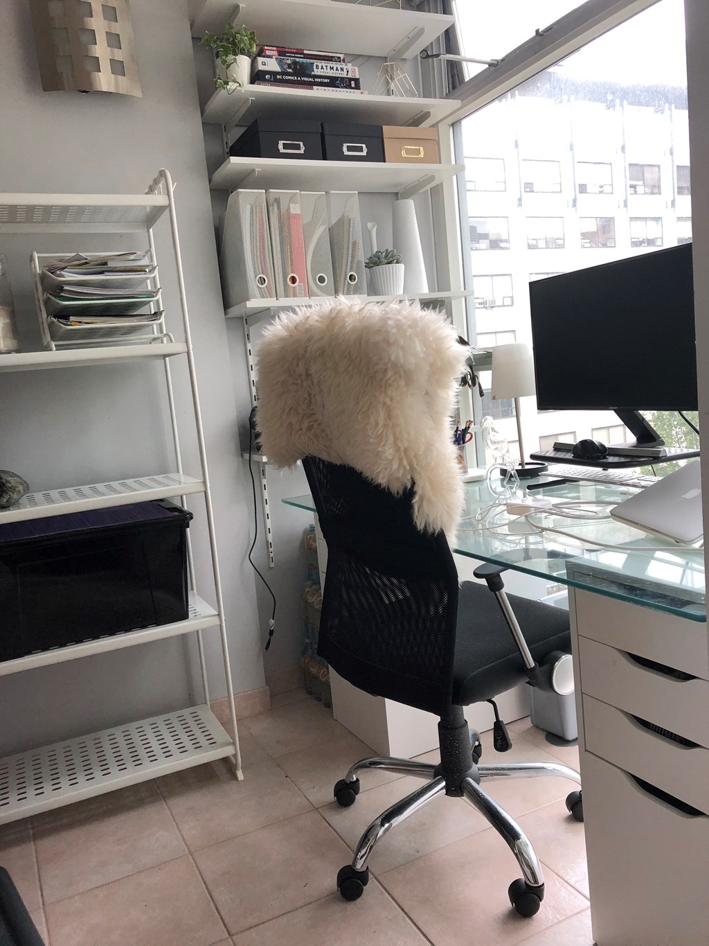 A white fluffy chair with wheels is in front of a desk with a computer monitor.