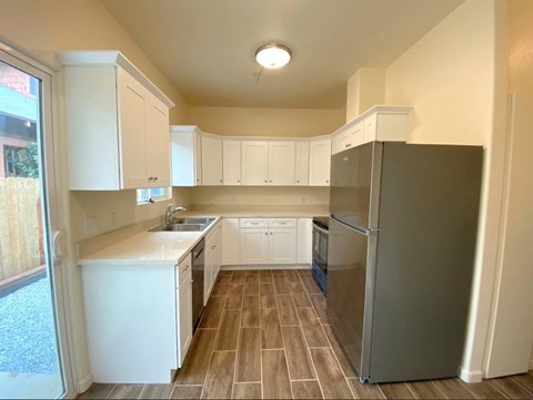 A kitchen with white cabinets and a black refrigerator.