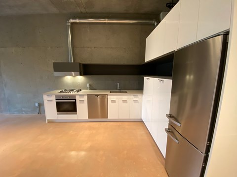 A modern kitchen with a stainless steel refrigerator and white cabinets.