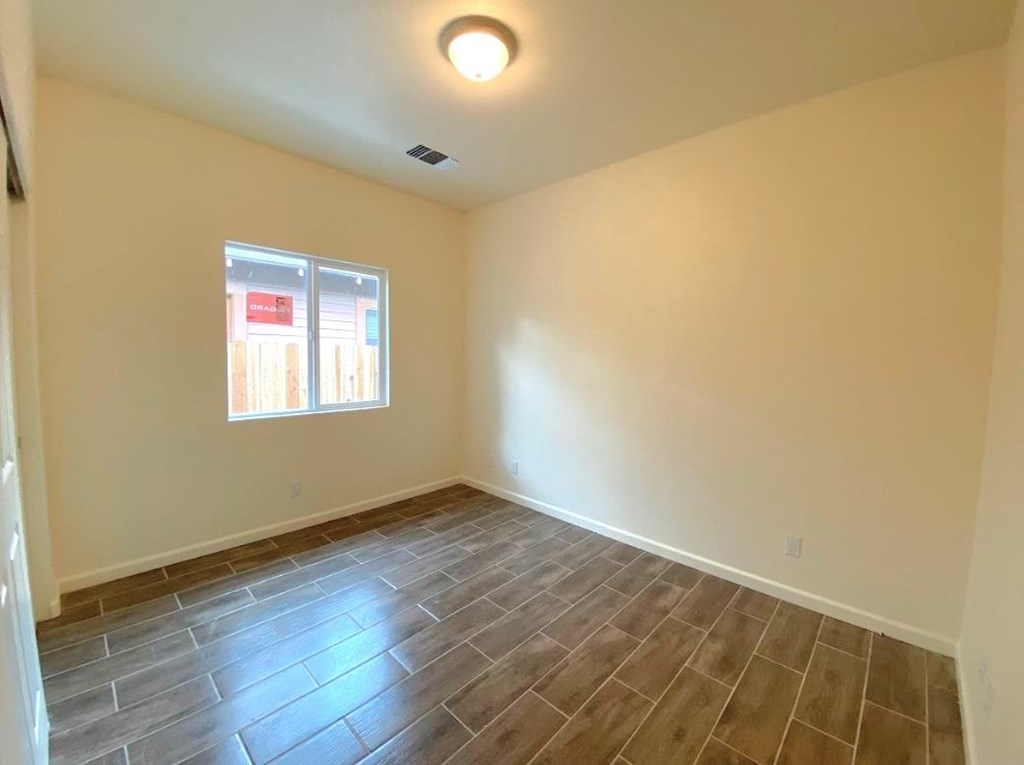 a empty room with wood flooring and a window