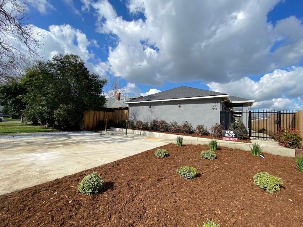 a house with a driveway and a yard with dirt and plants