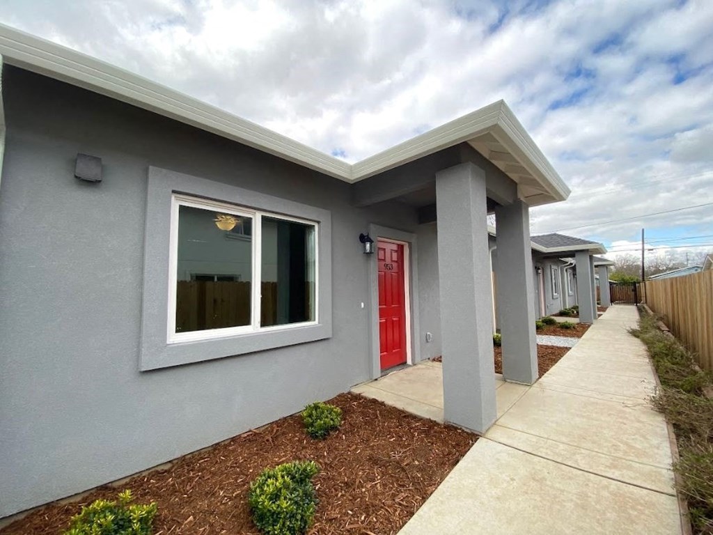 the front of a gray house with a red door
