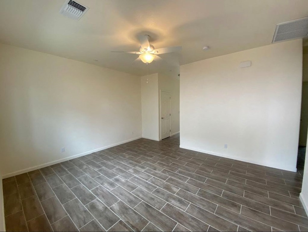 a empty living room with tile flooring and a ceiling fan