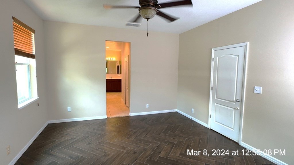an empty living room with wood flooring and a ceiling fan