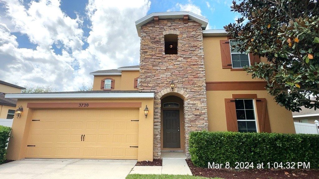 a house with a garage door and a stone tower on top of it