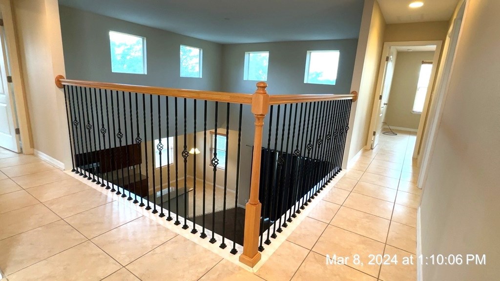 a staircase with a wooden banister and railing with tile flooring