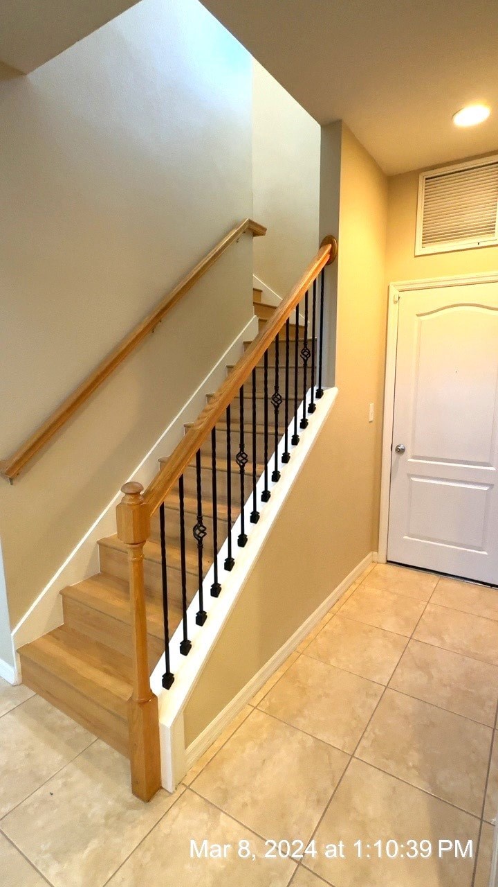 a staircase in a home with a white door and a wooden railing