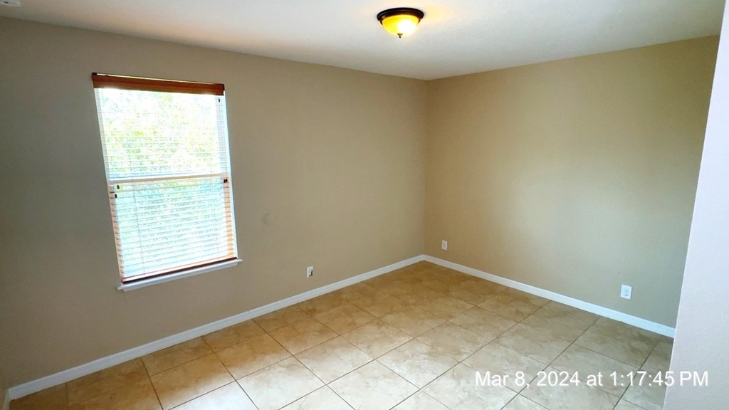 a empty dining room with a window and a tiled floor
