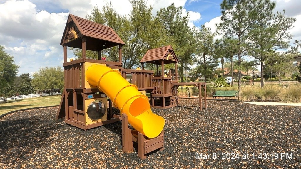 a playground with a yellow slide in a park