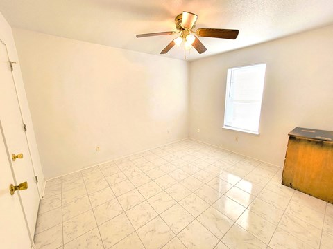 an empty living room with a ceiling fan and a tiled floor