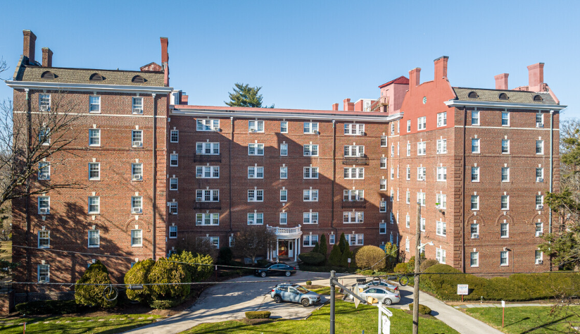 A large red brick building with a green lawn in front.