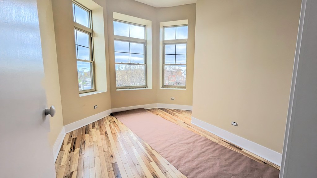 an empty room with a rug on the floor and three windows
