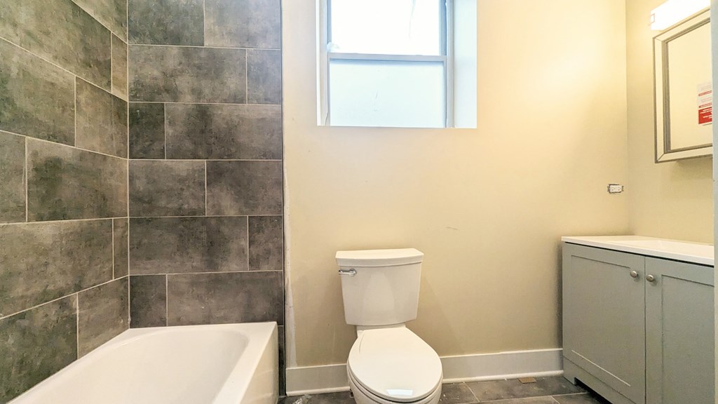 a bathroom with a toilet and a tub and a window