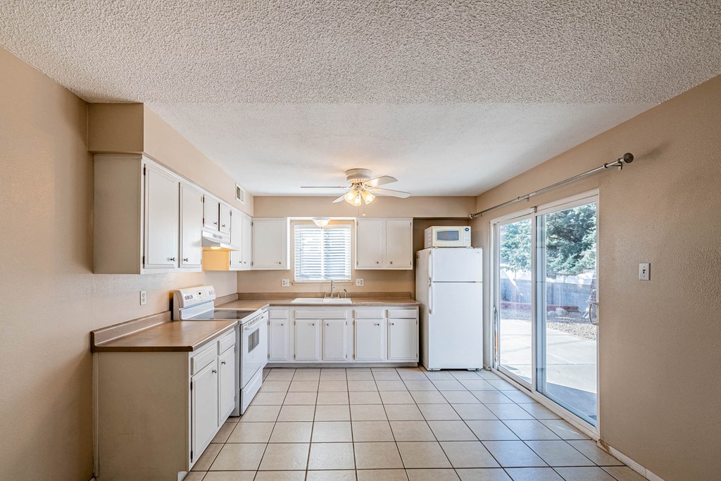 a kitchen with white cabinets and a sliding glass door