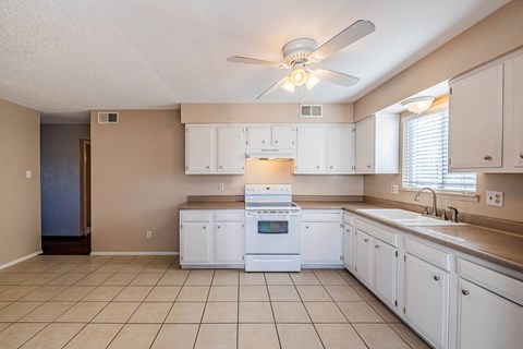 a kitchen with white cabinets and a ceiling fan