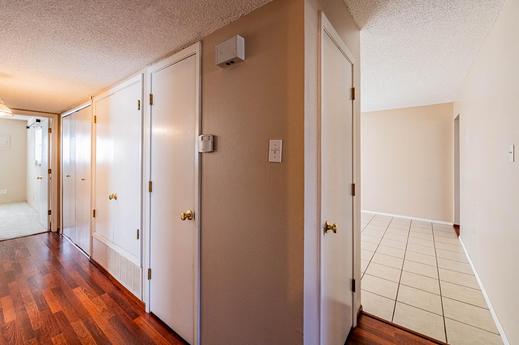 an empty hallway with wood floors and white closets