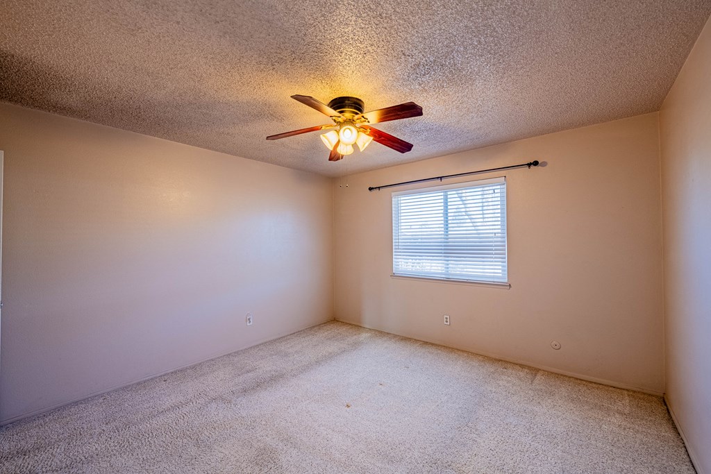 the bedroom of an empty house with a ceiling fan and a window