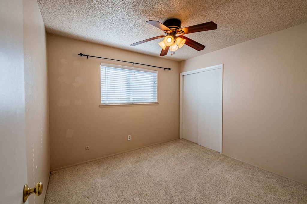 a bedroom with a ceiling fan and a door to a closet