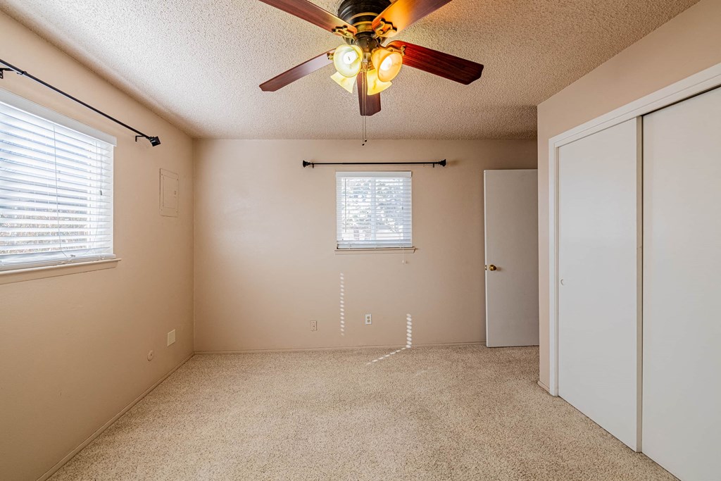a bedroom with a ceiling fan and a door to a closet