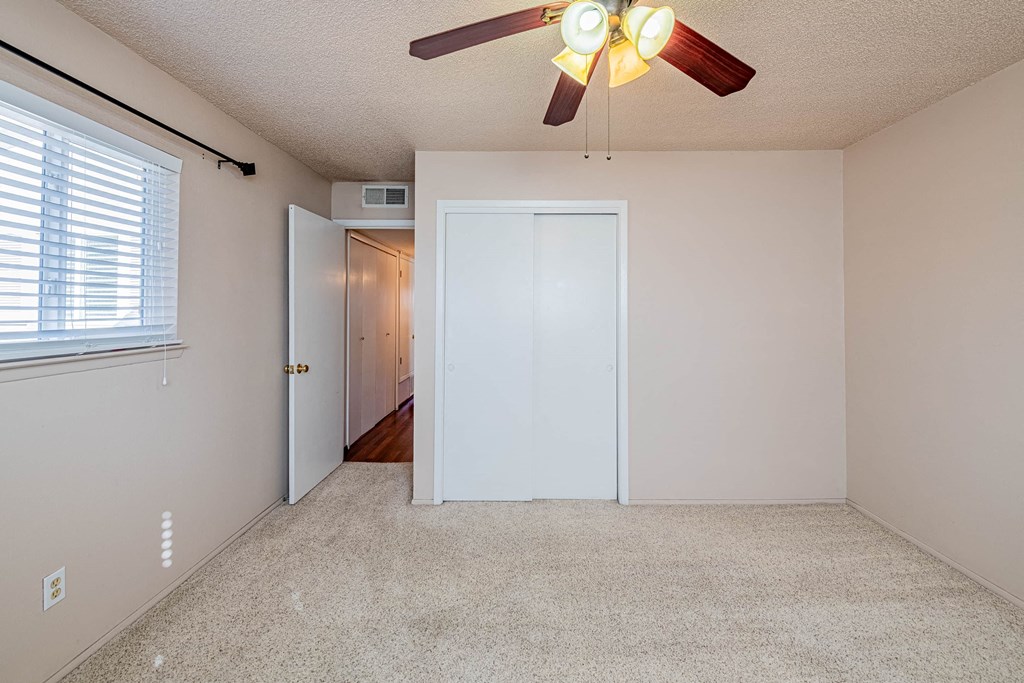 a bedroom with a ceiling fan and a door to a hallway