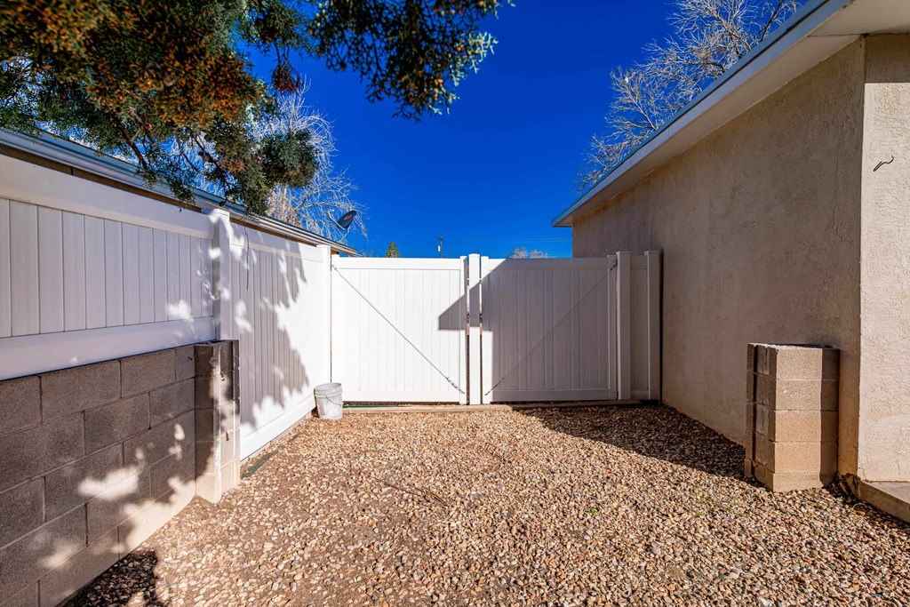 a white fence in front of a house with a gravel driveway
