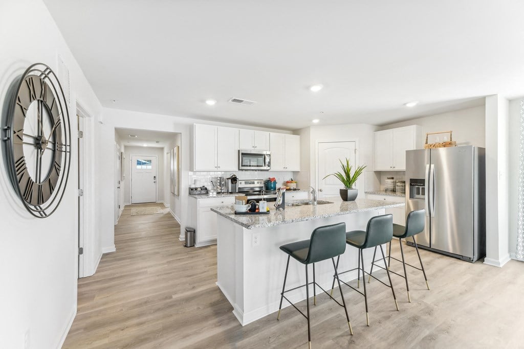 a white kitchen with a large island and stainless steel appliances