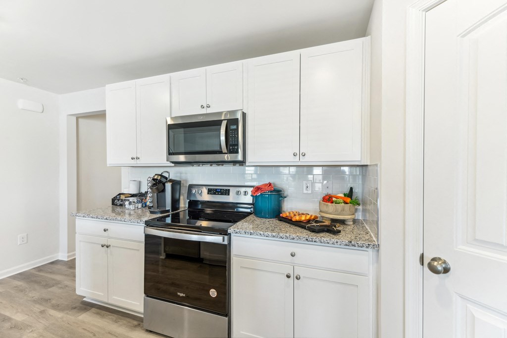 a white kitchen with stainless steel appliances and white cabinets