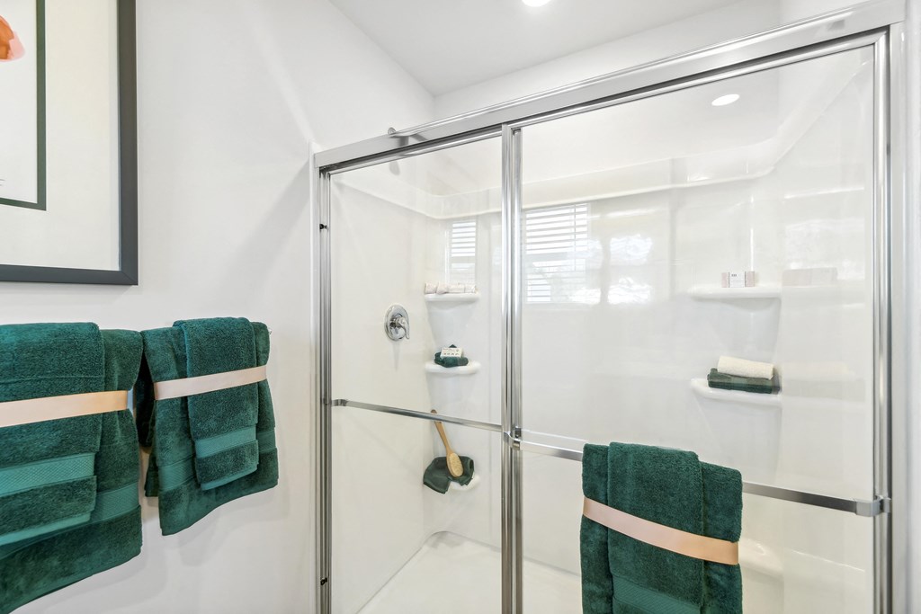 a bathroom with a glass shower door and green towels