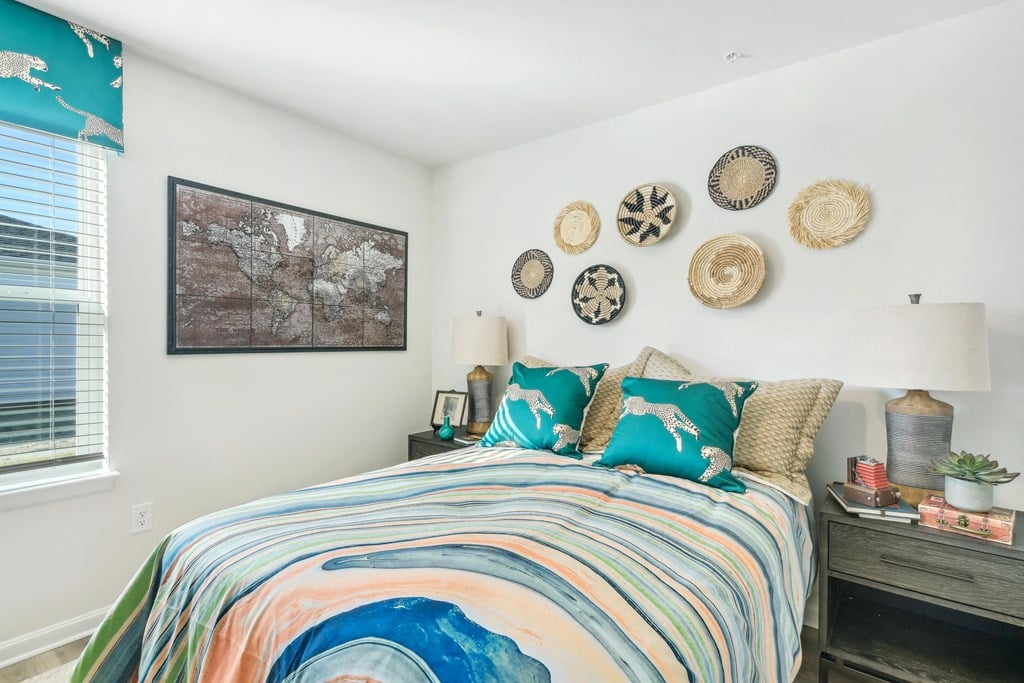a bedroom with a bed covered in colorful blankets and pillows