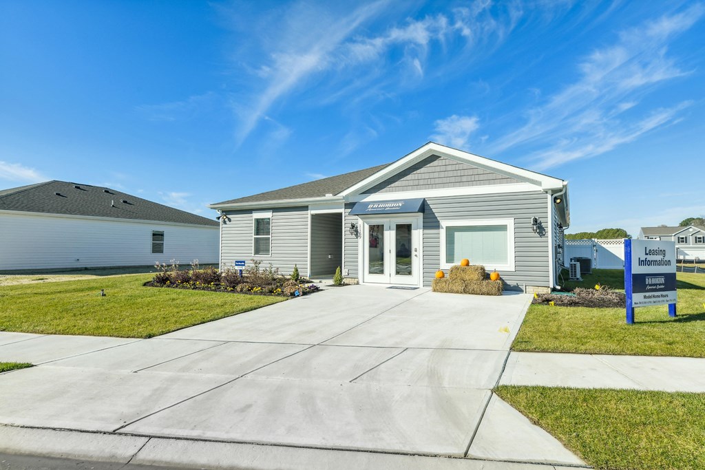 a small gray house with a sidewalk in front of it