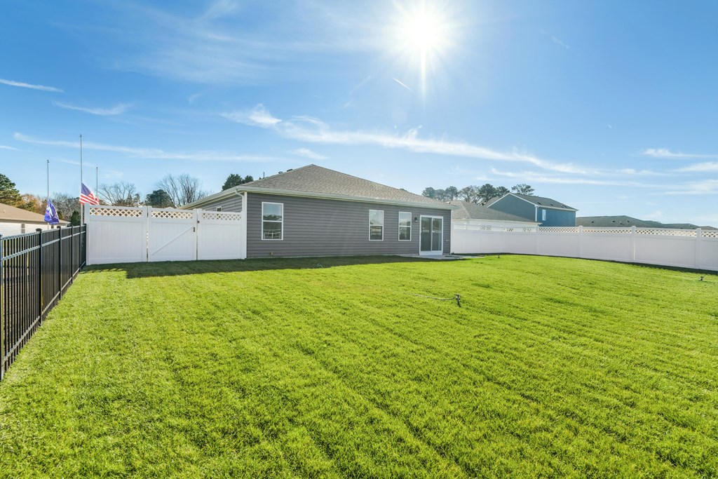 the back yard of a house with a grassy yard and a fence