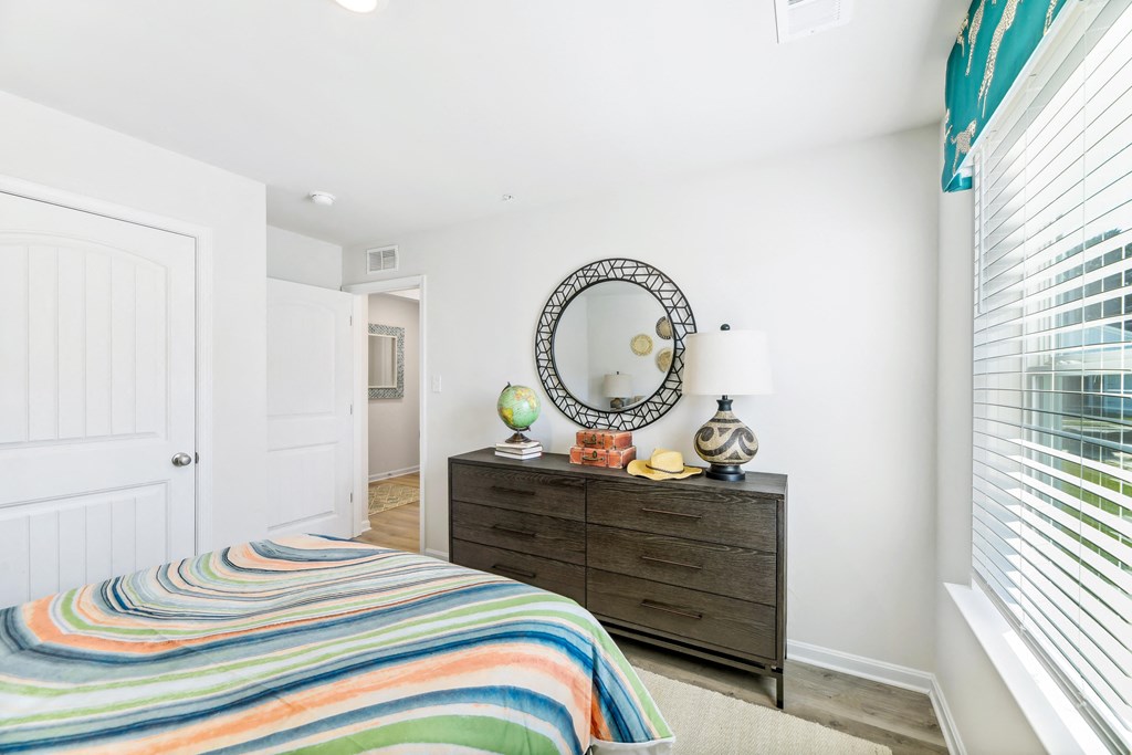 a bedroom with a bed and a dresser with a mirror