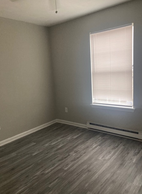 an empty room with a window and wooden floors