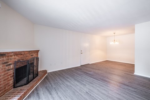 a living room with a brick fireplace and wooden floors