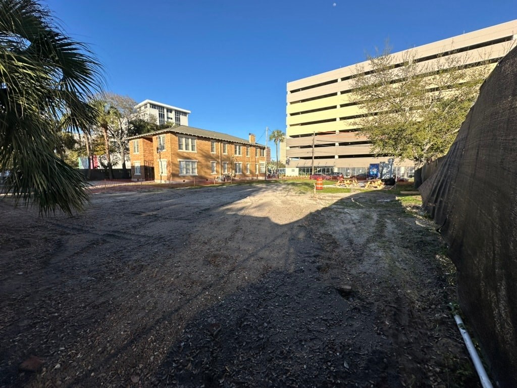 a city street with a building and a tree and a dirt road