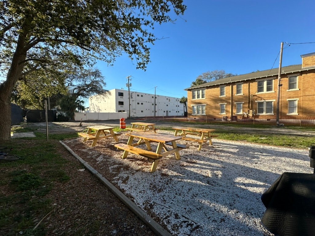a gravel area with picnic tables in front of a building