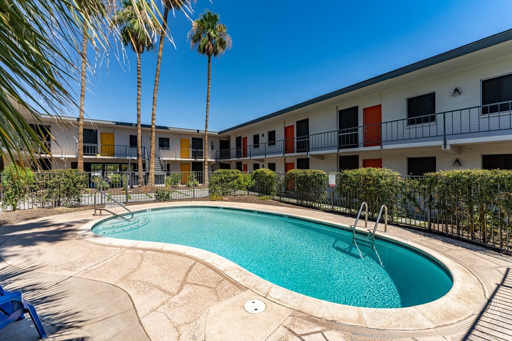 a swimming pool in front of a hotel with palm trees