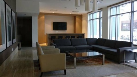 A modern living room with a black couch and a television.