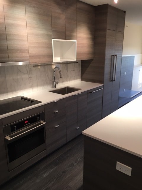 A modern kitchen with dark wood cabinets and stainless steel appliances.