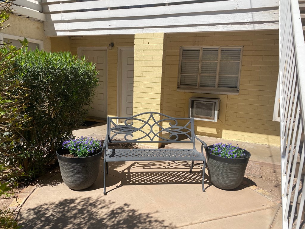 a bench on a patio in front of a yellow house
