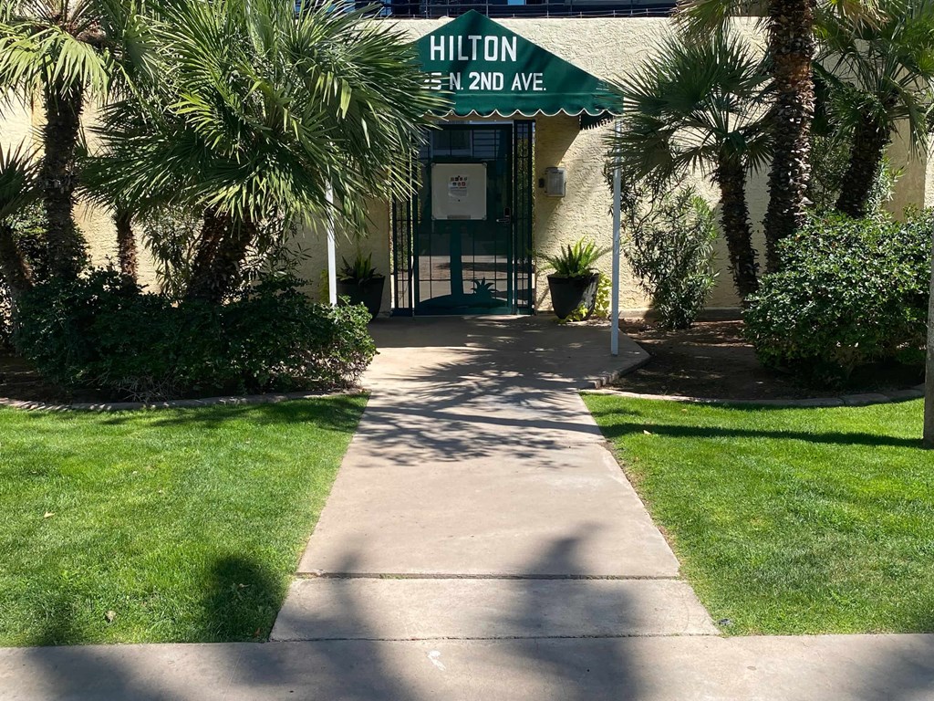 a sidewalk in front of a building with a green street sign