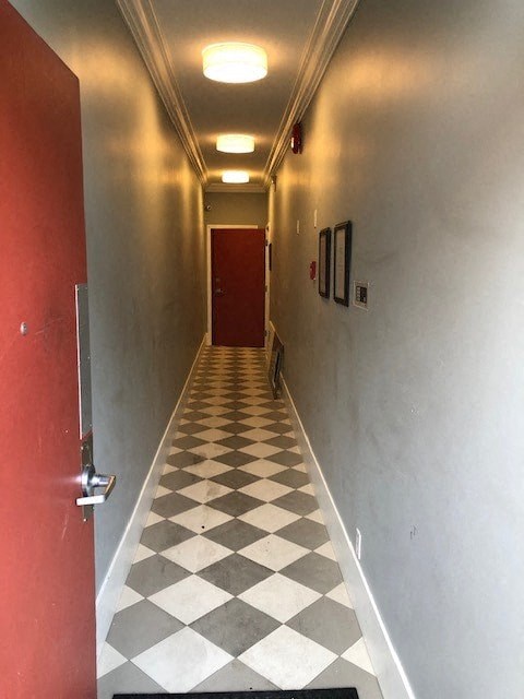 a hallway with a checkered floor and a red door