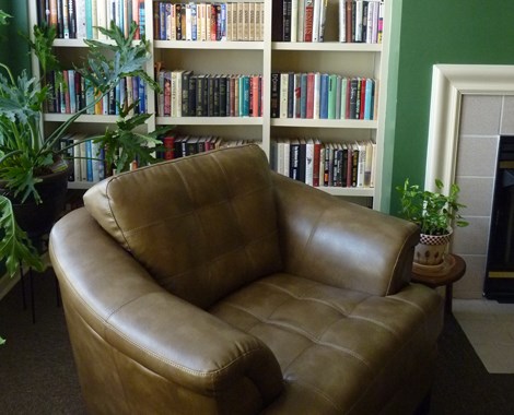 a brown leather chair in front of a book shelf