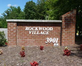 the sign for rockwood village in front of a brick wall