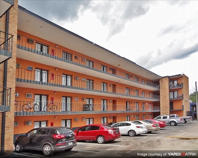 an apartment building with cars parked in a parking lot