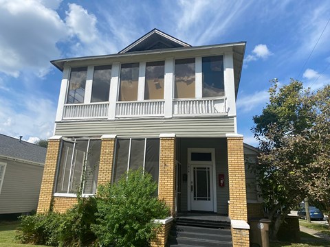 the front of a brick house with a white porch