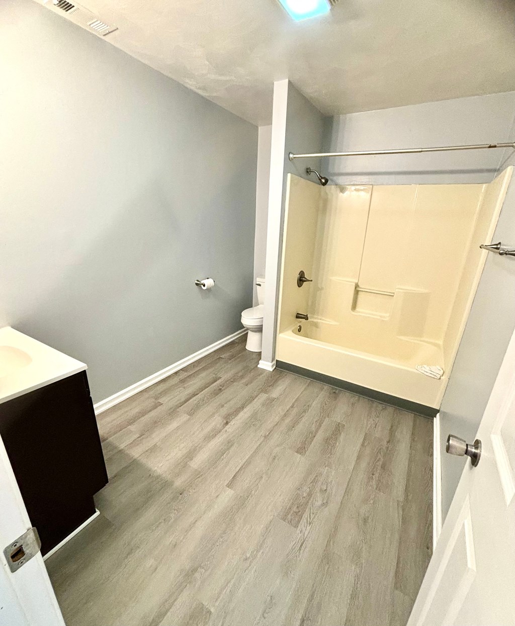 an empty bathroom with wood flooring and a shower