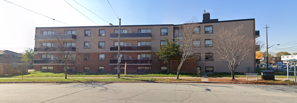 A large brick apartment building with a parking lot in front.