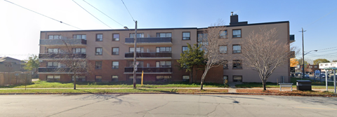 A large brick apartment building with a parking lot in front.