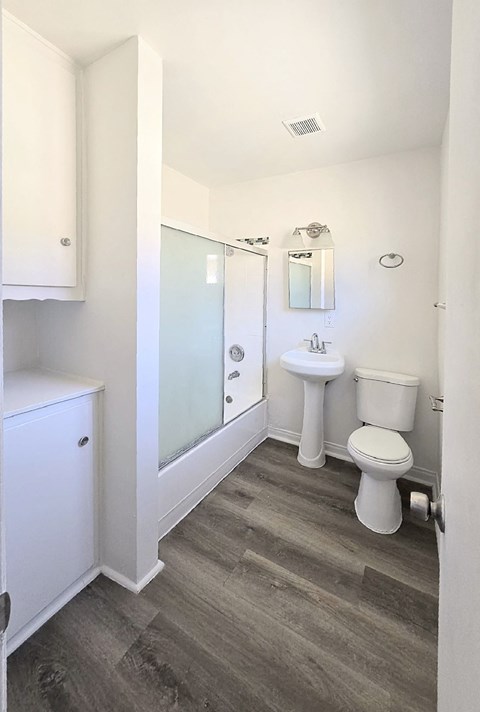 A bathroom with a toilet, sink, and shower.